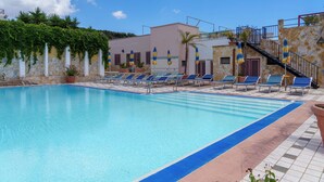 A swimming pool with lounge chairs and a staircase leading to a building. - HOTEL LE MACINE (Santa Cesarea Terme)