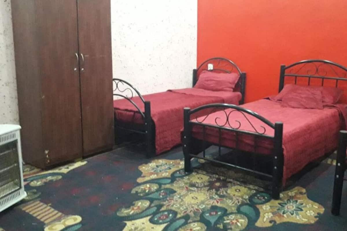 A room with three single beds, a wardrobe, and a radiator.