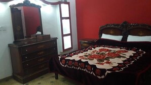 A bedroom with a bed, dresser, and a mirror. - Wadi Rum Village Lodge (Wadi Rum)