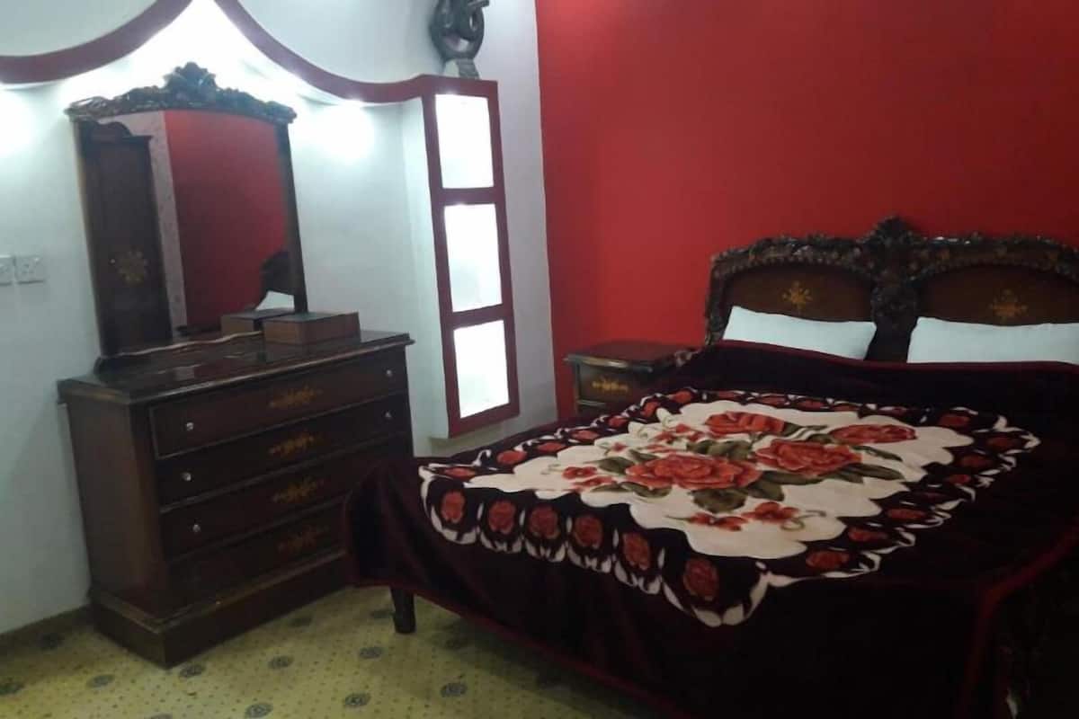 A bedroom with a bed, dresser, and a mirror.