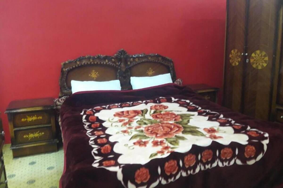 A bedroom with a bed, wooden headboard, and a nightstand.