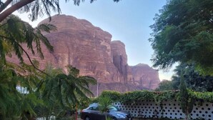 A courtyard with a car, a bench, and a fence with circular cutouts. - Wadi Rum Village Lodge (Wadi Rum)