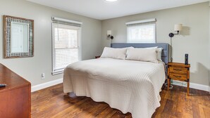 Un dormitorio con cama, mesitas de noche y cómoda.