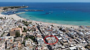 Vue aérienne d’une ville côtière avec une plage, des bateaux et des bâtiments.