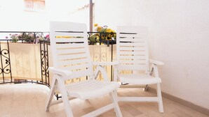 Deux chaises en plastique blanc, dotées d’un dossier et de bras à lattes, sont placées sur un plancher en bois.