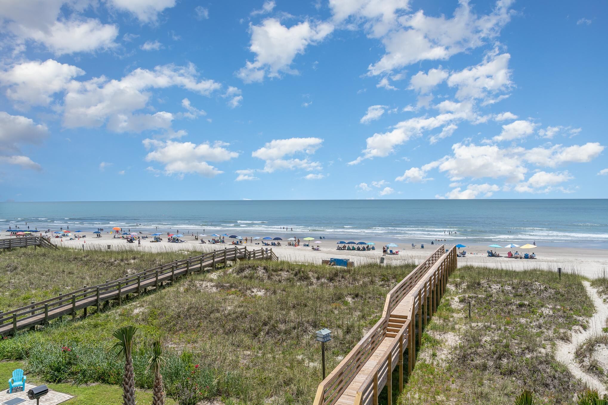 A beach with a wooden boardwalk, sandy beach, and ocean view.