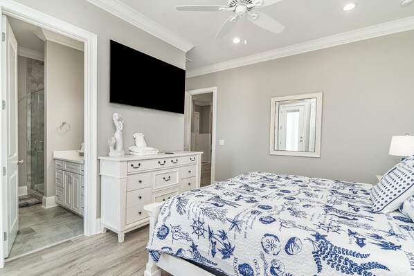 A bedroom with a bed, a dresser, a television, and a walk-in closet.