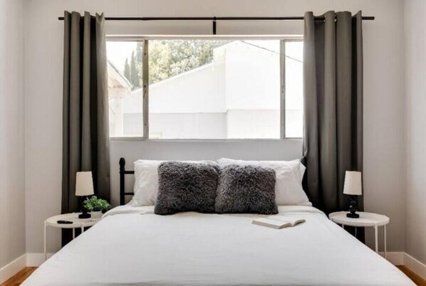 Relax in a serene space with a large bed, two bedside tables, and a window with natural light.