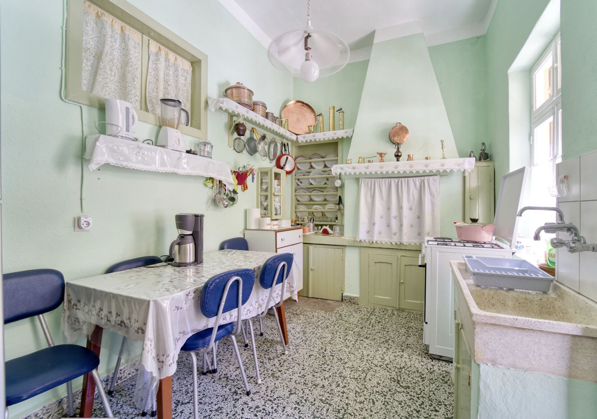 A kitchen with a dining table, chairs, a stove, and various kitchen utensils and appliances.