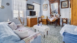 A traditional room with a sofa, a television, a wooden cabinet, a dining table, and a mirror. - 2islands Waterfront House (Symi)