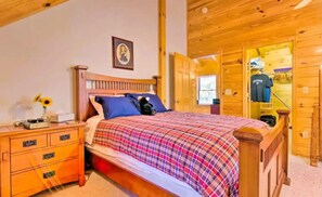 Un dormitorio de madera con cama, mesita de noche y cómoda.