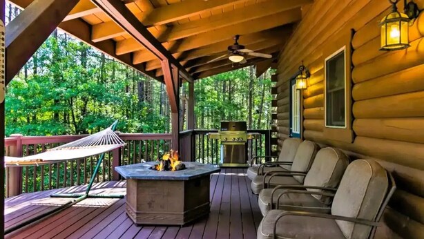 Eine Holzterrasse mit Feuerstelle, Sitzgelegenheiten im Freien und einem Grill.