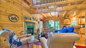 Ein gemütliches Blockhaushaus-Interieur mit Kamin, Holzwänden, einem Essbereich und einer Küche.