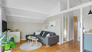 A modern living room with a grey sofa, a small round table, and a potted plant. - 3 bedroom nice home in Hejls (Hejls)