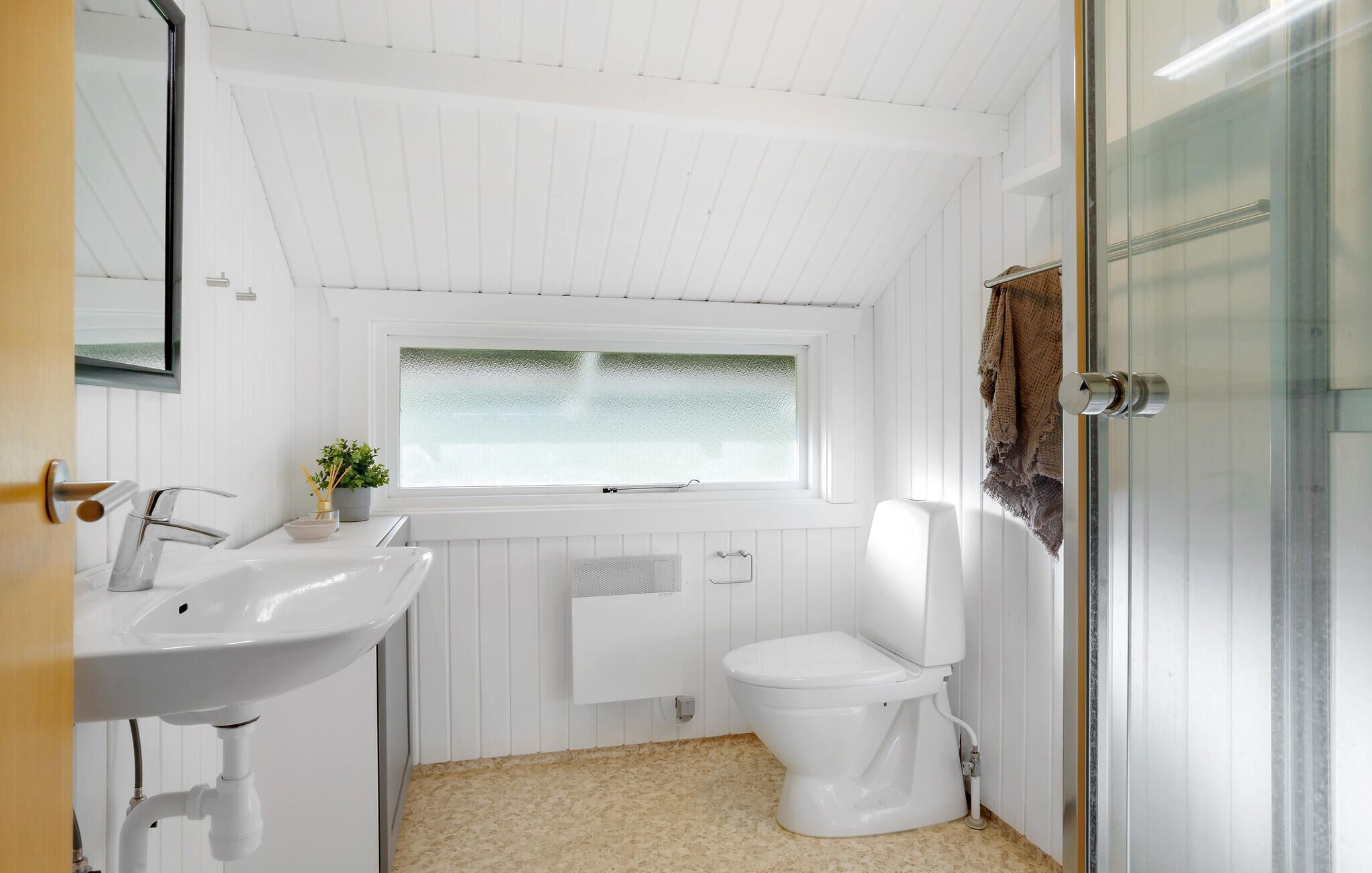 A bathroom with a white sink, toilet, and a window with frosted glass.