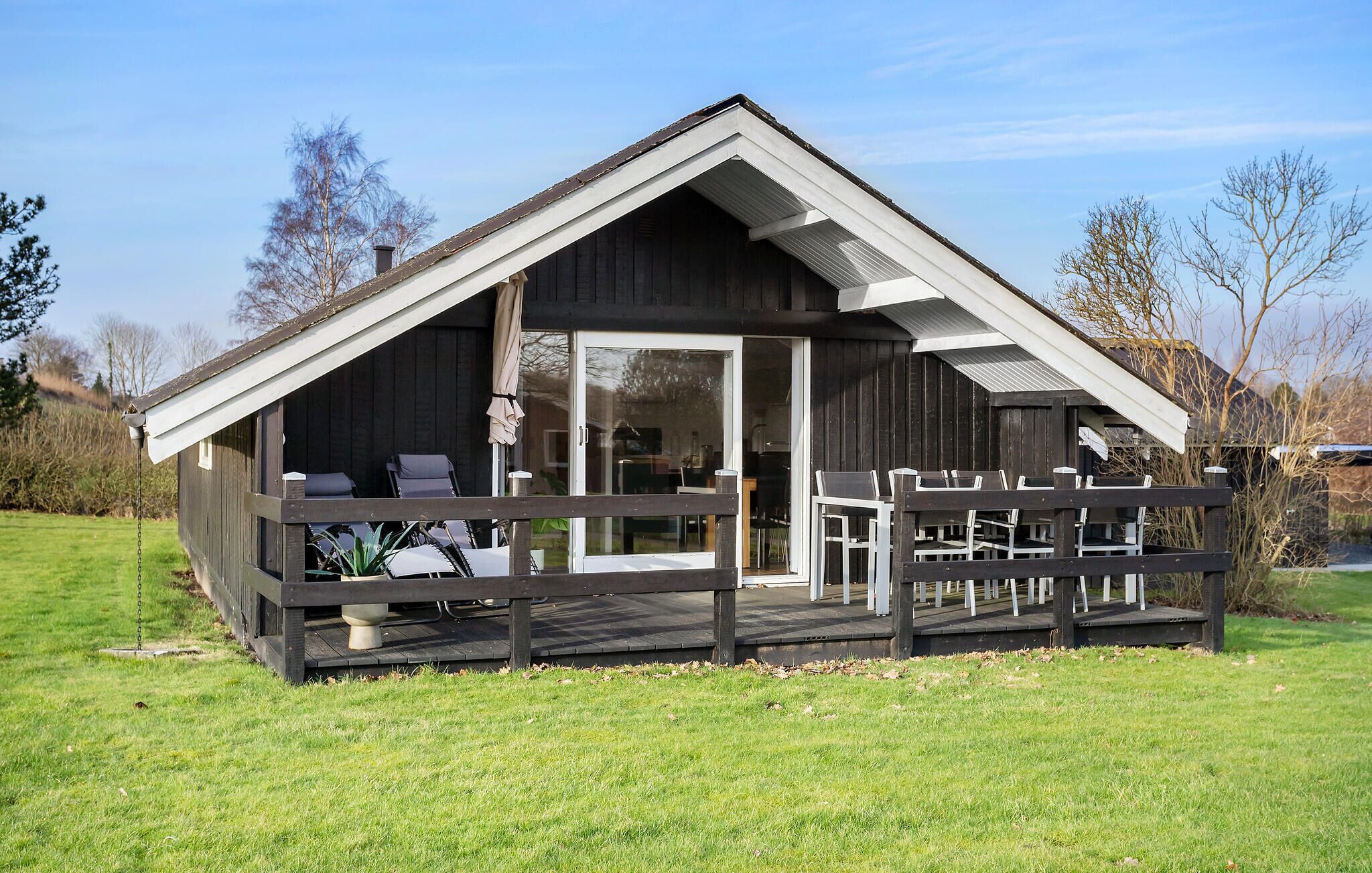 Une cabane en bois dotée d’une véranda, d’un coin repas et d’une porte vitrée donnant sur l’intérieur.