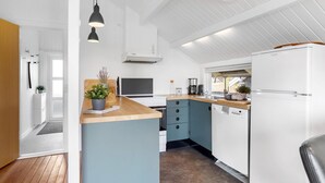 A modern kitchen with white cabinets, a wooden countertop, and a built-in oven. There is a window providing natural light and a hanging light fixture above the counter. - 3 bedroom nice home in Hejls (Hejls)