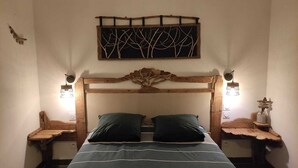A bedroom with a wooden headboard, two bedside tables with lamps, a bed with striped bedding, and a wall-mounted artwork above the bed.