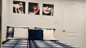 Un dormitorio con una cama, una puerta y tres cuadros colgados en la pared.