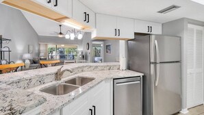 A modern kitchen with granite countertops, stainless steel appliances, and white cabinetry.