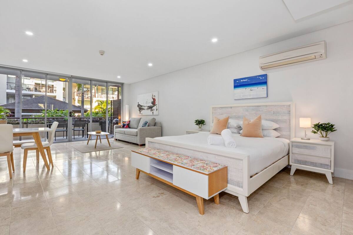 Una camera da letto moderna con un letto grande, una scrivania e un balcone con vista sulla città.