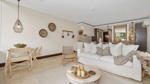 Una sala de estar moderna con un sofá blanco, sillas de madera, una mesa de comedor y una mesa de centro con adornos.
