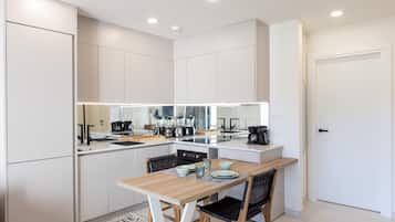 A modern kitchen with white cabinetry, a wooden dining table, and black chairs.