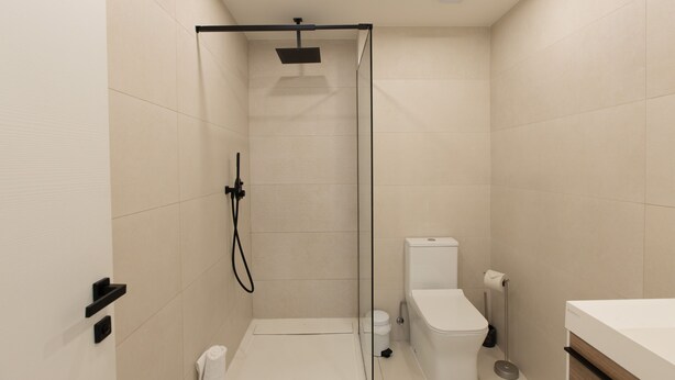 A modern bathroom with a glass-enclosed shower, a toilet, and a sink. - A111 - Condo with amazing view (Sint Maarten)