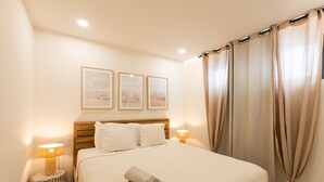 A neatly made bed with a rolled towel, two bedside lamps, and three framed pictures on the wall. - A111 - Condo with amazing view (Sint Maarten)