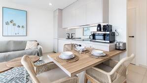 A modern kitchen with white cabinets, a dining table with chairs, and a coffee maker. - A111 - Condo with amazing view (Sint Maarten)