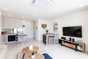 A modern living space with a kitchen, dining area, and a TV mounted on the wall.