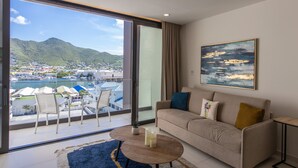Una habitación de hotel moderna con balcón, un sofá, una mesa de centro y un cuadro.