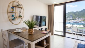 Una habitación moderna con una mesa de comedor de madera, un televisor de pantalla plana y vistas a un puerto deportivo y montañas.