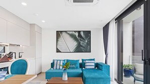 A modern living room with a teal sofa, a wooden coffee table, and a large window. - A136 - Amazing Spacious Apartment Lagoon View with Balcony (Sint Maarten)