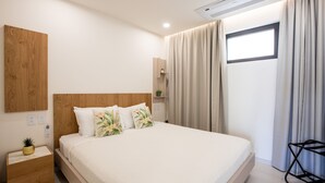 A modern bedroom with a wooden headboard, a white bedspread, and a small bedside table with a plant. - A112 - Extraordinary Lagoon View with Balcony (Sint Maarten)