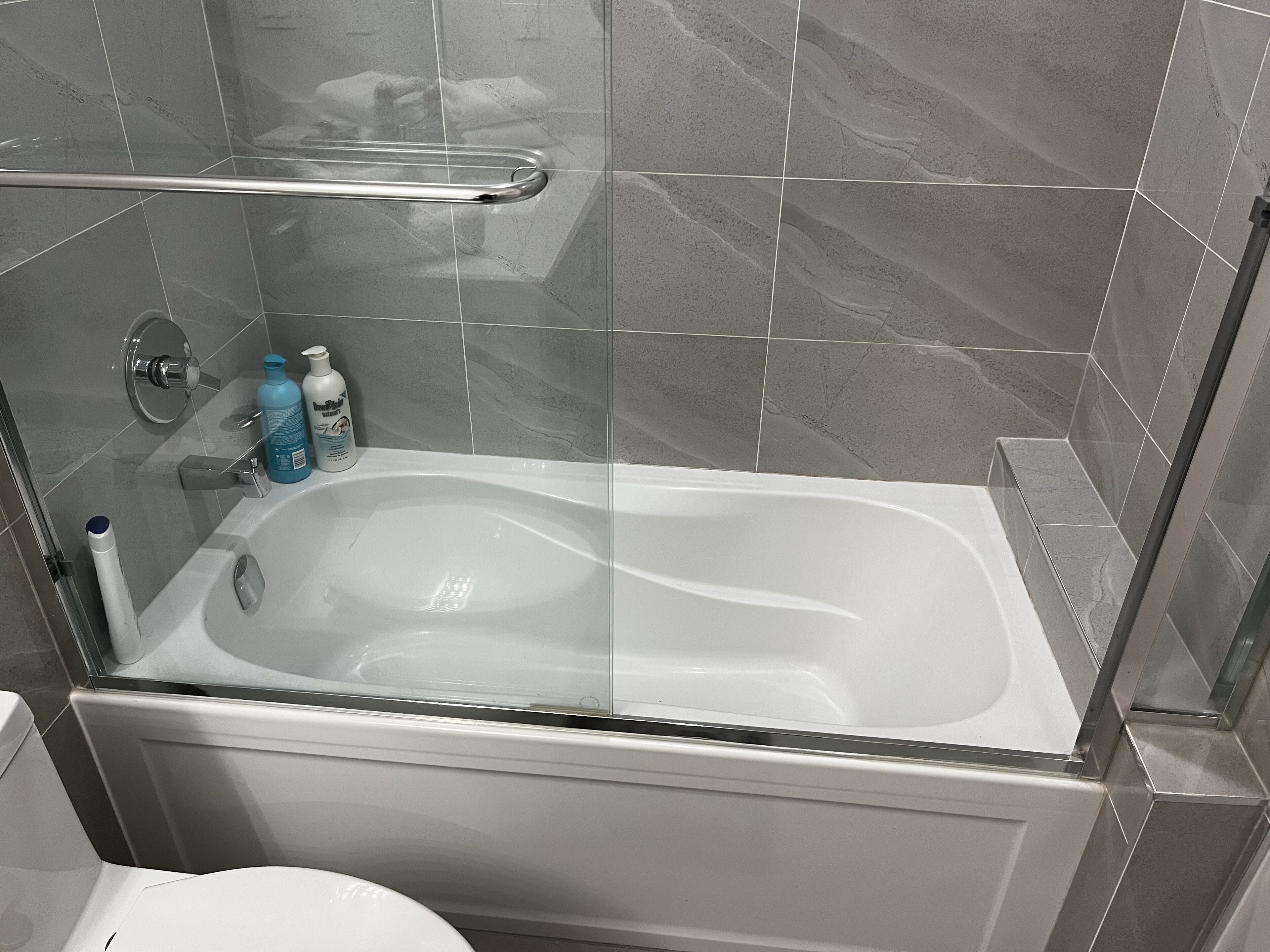 Un bagno moderno con vasca da bagno vetrata, zona doccia e toilette.