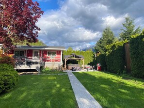 Stunning home with a garage, outdoor seating area, and beautifully manicured lawn, set amidst lush greenery and a scenic mountain backdrop.