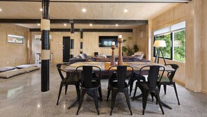 Un espace repas moderne avec une table ronde, des chaises noires et un mur d’accent en bois.
