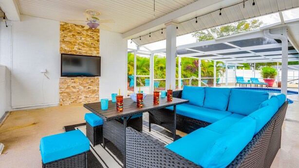 An outdoor patio with a sofa, table, and TV.