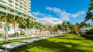 A hotel with a pool area, palm trees, and a well-maintained lawn. - FontaineBleau Resort Ocean plus Bay View w/ Balcony (Miami Beach)