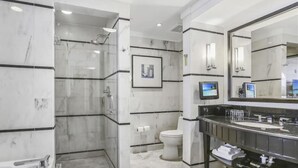 A modern bathroom with a glass-enclosed shower, a toilet, a large mirror, and a vanity with a sink and countertop. - FontaineBleau Resort Ocean plus Bay View w/ Balcony (Miami Beach)
