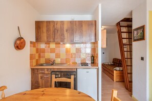 Una cucina compatta con mobili in legno, una lavastoviglie piccola e un tavolo da pranzo.