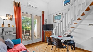 A modern living room with a sofa, dining table, chairs, a TV, and a staircase.