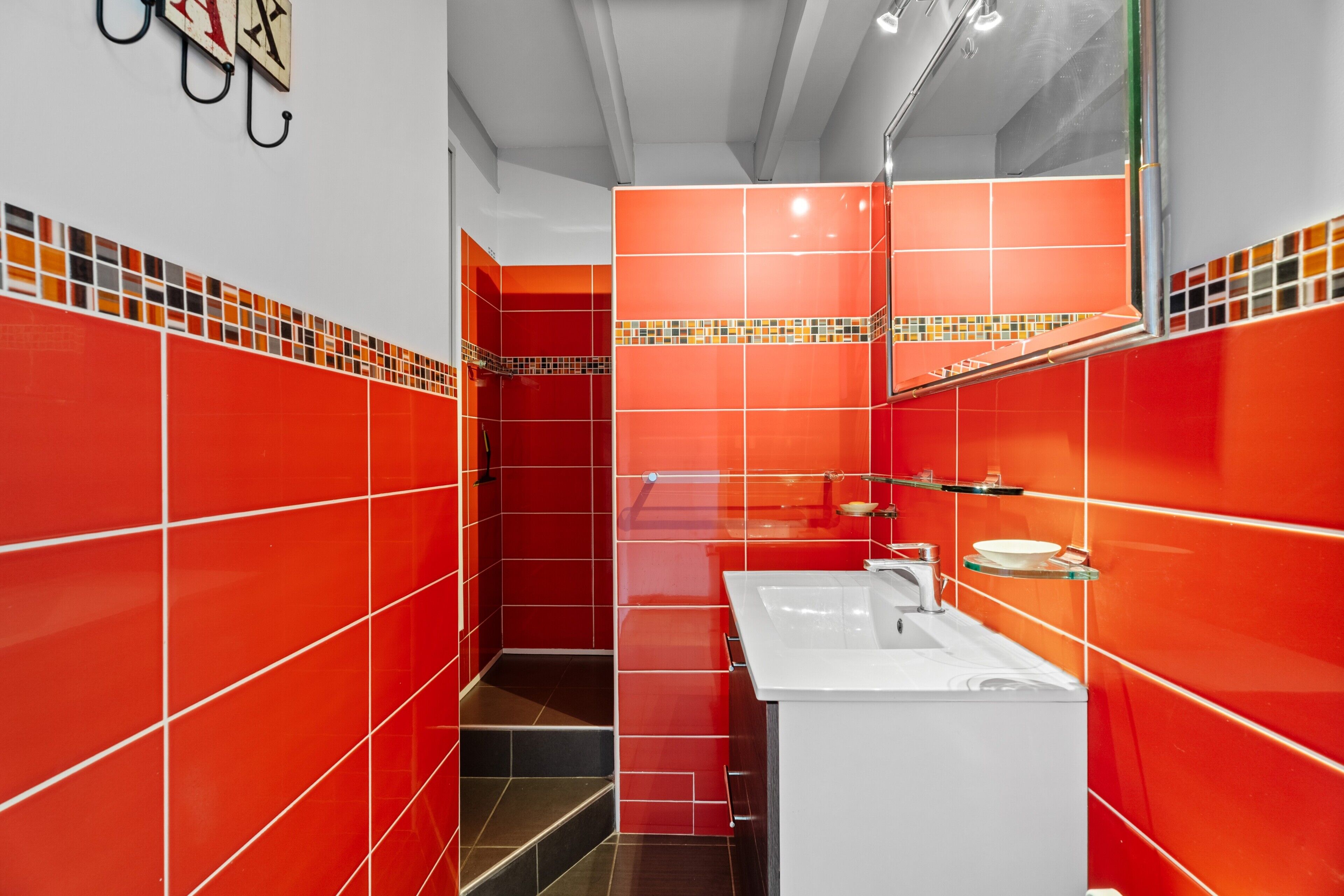 Un baño con baldosas rojas, un lavamanos blanco y un espejo.