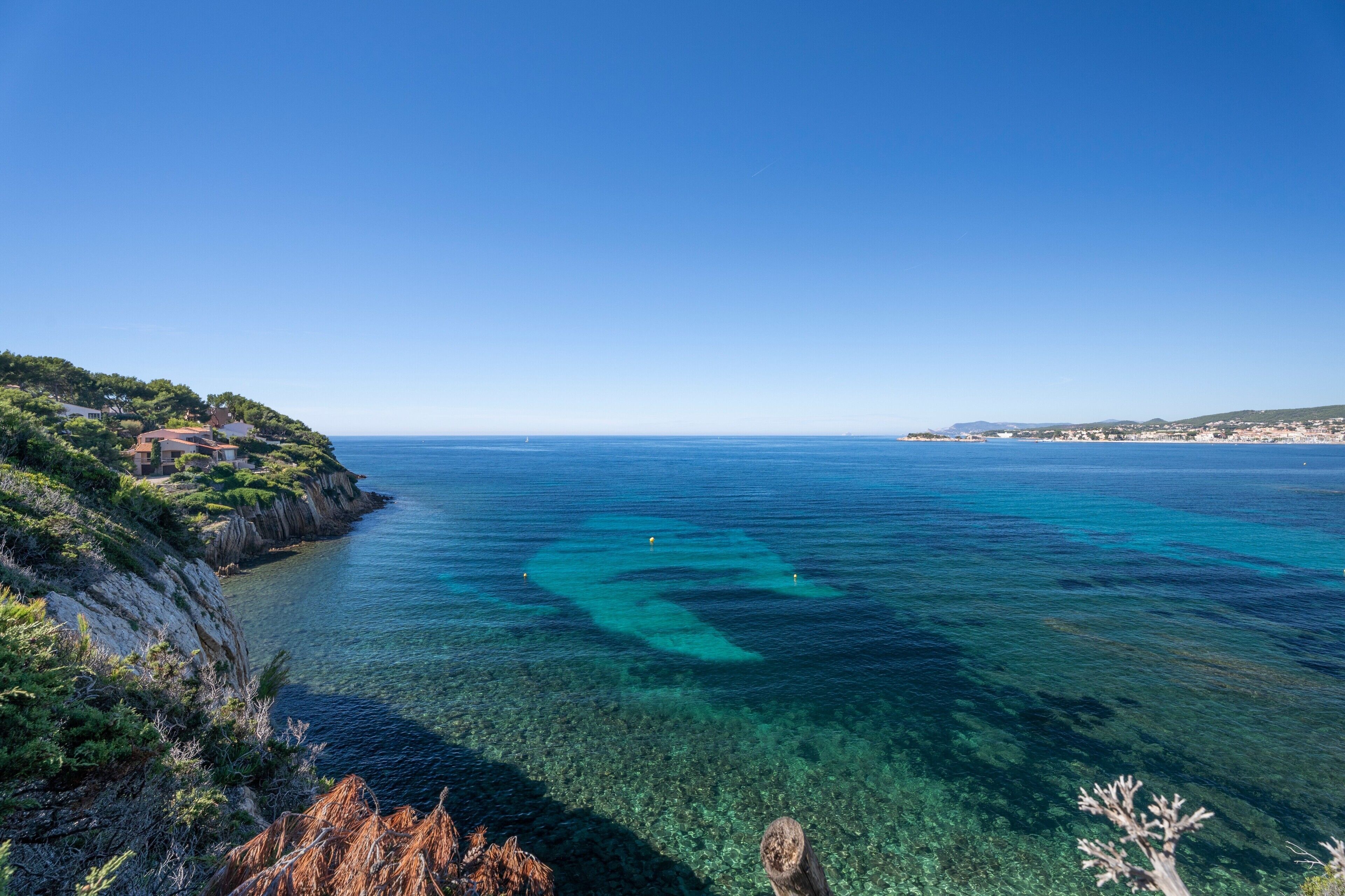 Eine Küstenlandschaft mit klarem türkisblauem Wasser, felsigen Klippen und spärlicher Vegetation.