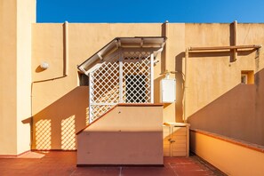 Un coin d’un bâtiment avec une porte blanche, une petite fenêtre et un escalier en métal.