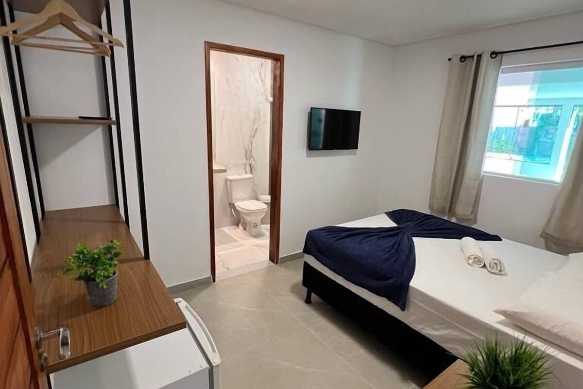 A modern bedroom with a bed, a TV, a desk, and a wardrobe.
