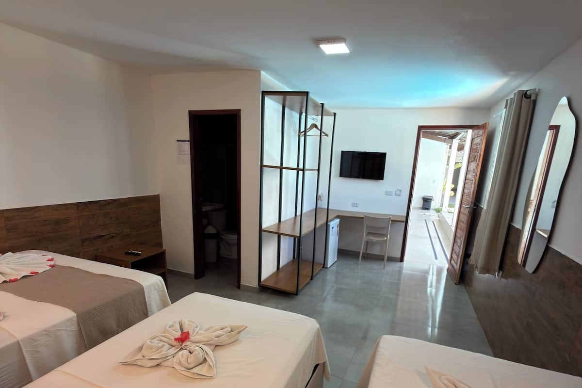 A hotel room with two beds, a desk, a TV, and a bathroom.