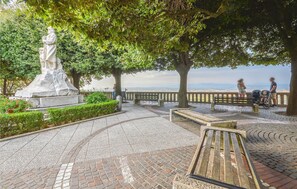 Un parc avec une statue, des bancs et une zone dallée offrant une vue panoramique.