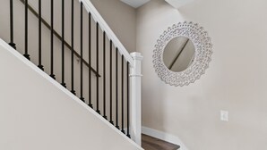 A staircase with black balusters and white handrails, leading to a landing with a decorative mirror. - Mtn Views, 20 Mins to Asheville, 12 Mins to Skiing, Arcade Games (Mars Hill)
